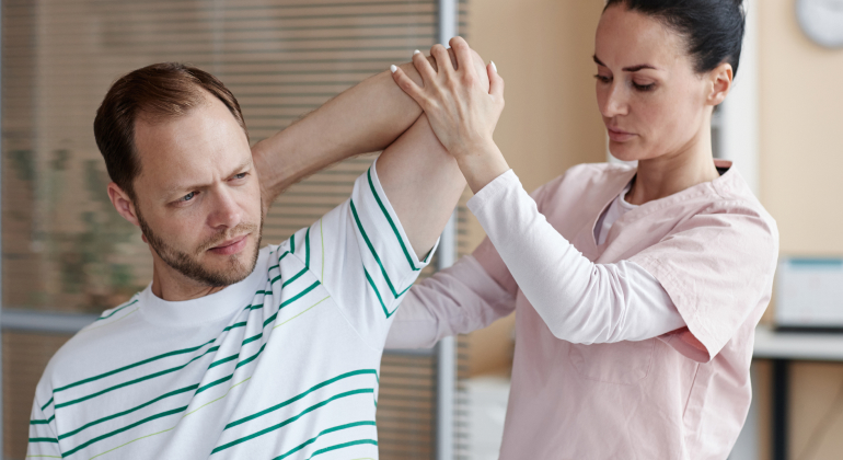 Physical therapist assisting a man with arm stretches to prevent trigger points and nerve compression in a clinical setting.