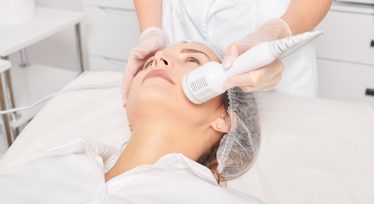 A person receiving a cryotherapy facial, with a handheld device applying cold treatment to the face for skin rejuvenation and tightening.