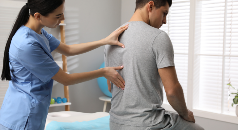 Physiotherapist assessing a patient's back pain during a rehabilitation session