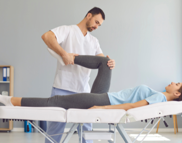 Physiotherapist performing leg mobility exercises on a female patient during a rehabilitation session to improve flexibility and recovery.