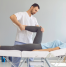 Physiotherapist performing leg mobility exercises on a female patient during a rehabilitation session to improve flexibility and recovery.