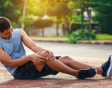 Man experiencing knee pain after a sports injury, holding his knee in discomfort