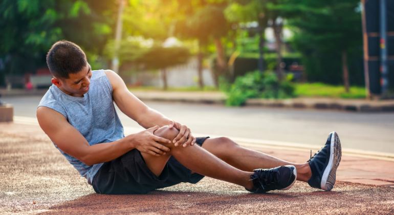 Man experiencing knee pain after a sports injury, holding his knee in discomfort