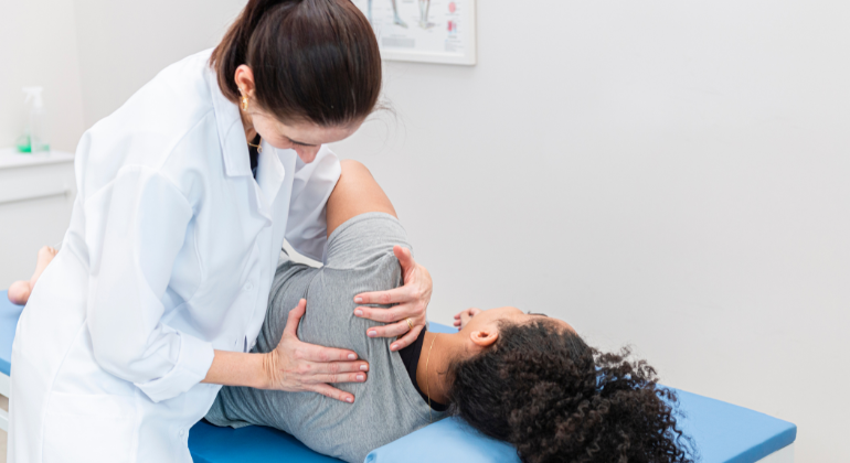 Physiotherapist performing manual therapy on a patient's shoulder to relieve pain