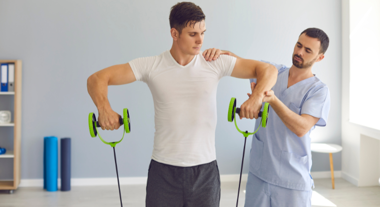 Physiotherapist guiding a male athlete through shoulder rehabilitation exercises using resistance bands during a sports injury recovery session.