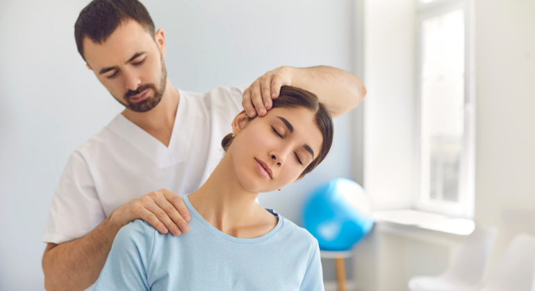 Physiotherapist performing neck therapy on a female patient during a rehabilitation session, gently stretching her neck for pain relief.