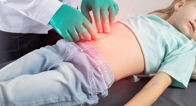 A healthcare professional wearing green gloves examines a child’s abdomen, with a highlighted red area indicating abdominal discomfort or a condition like navel displacement. The image represents medical evaluation and treatment for abdominal issues.