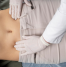 Practitioner assessing abdominal alignment and navel position during a physical examination.