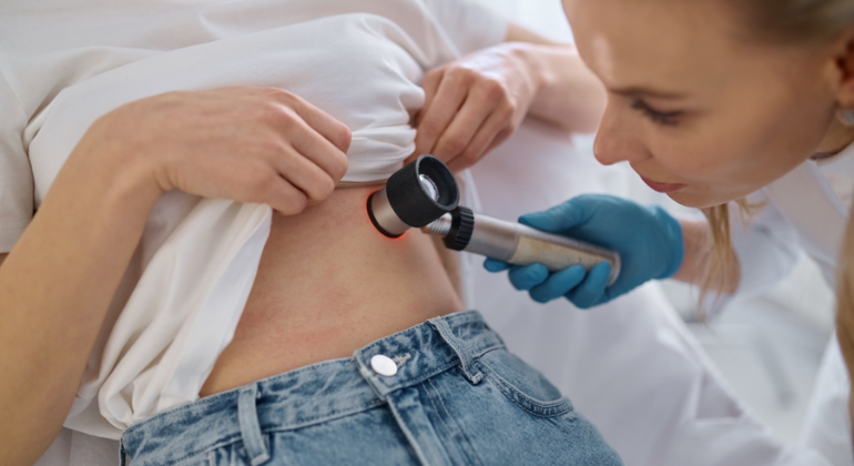 Female doctor examining a woman’s abdominal area for signs of navel displacement using a medical tool.